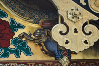 A cobalt elephant peaks out from gold gilt carvings atop the shrine roofs.